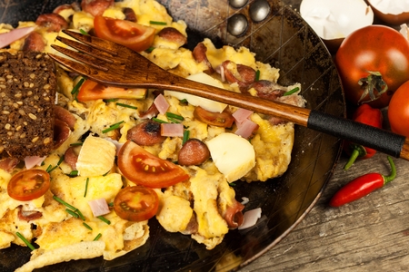 Fresh scrambled egg with ham and chilli peppers on a steel pan. A nourishing traditional breakfast.  Calorie mealsの写真素材