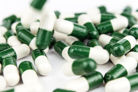 green-white pills on a white background. Pharmaceutical industry. Development of new drugsの写真素材