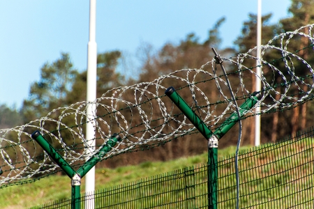 Fence with razor barbed wire. Guarded area. Military base. Razor wire