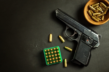 Pistol on black background. Gun and cartridges on the table. Right to hold a gun
