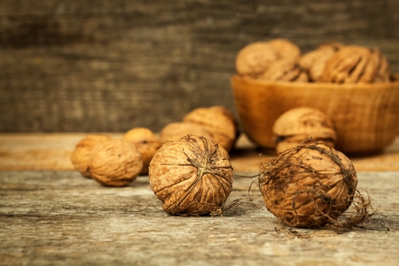 Walnut kernels and whole walnuts on a rustic old wooden table. Food photography. Autumn harvest....
