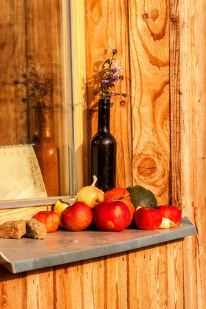 Apples laid on a window sill of a wooden house. Evening on the farm. Autumn time. Fruit harvestの写真素材