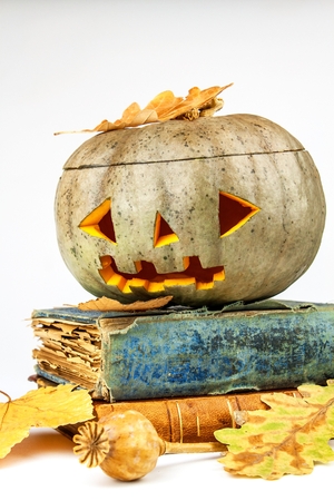 Halloween Pumpkin with books on white background. Halloween Pumpkin, funny Jack O'Lantern. Evil faces a spooky holidayの写真素材