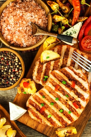 Grilled pork chop on a wooden board. Protein food. Grilled meat. Food preparation. Protein diet.の写真素材