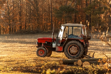 Old red tractor on the edge of a forest. Work in forest. An abandoned tractor. Landscape of the Czech countryside.の写真素材