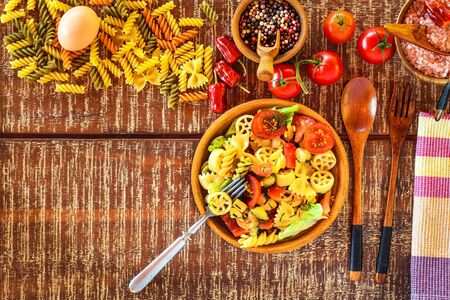 Pasta salad with cheese. Summer salad.  Pasta with vegetables on wooden table.の写真素材