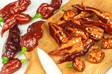 Slicing extra hot chili peppers (Bhut Jolokia Chocolate). Preparation for drying. Sale of hot...