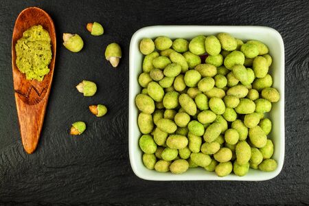 Wasabi Coated Peanuts on slate board. Japanese Wasabi Spice. Green wasabi peanuts on a black plate on a dark background.の写真素材