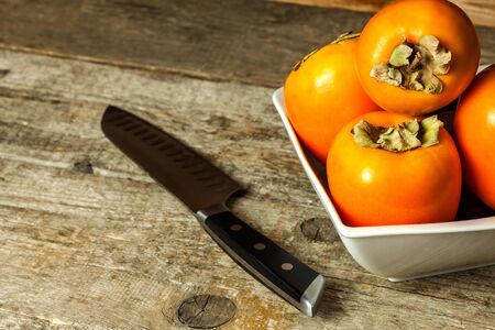 Ripe orange persimmon fruit.Kaki fruit on wooden table.Slices of persimmon.Set of kakis. Fruits of...