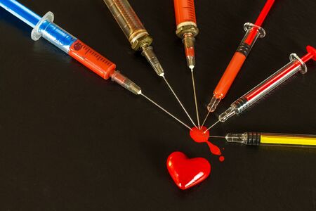 Syringe and blood on black background. Risk of HIV infection. Flu vaccination. Blood test. Old syringeの写真素材