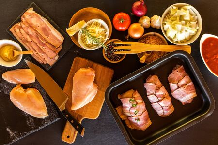 Raw chicken and bacon on the table top. Ingredients for healthy food. Chicken breast with tomatoes.