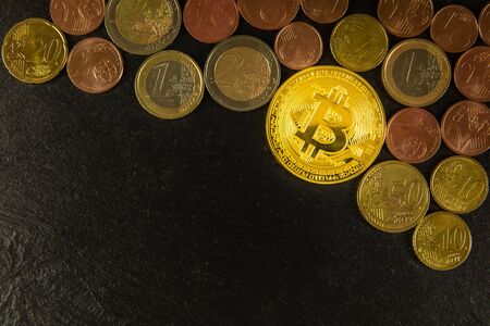 Golden bitcoin coins and euro coins on black slate background.  Investment in virtual currency. European finance.の写真素材