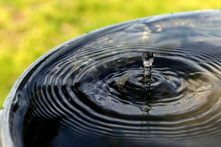 Impact of a drop of rainwater on a full barrel. Saving water on the farm. Water for watering.の写真素材