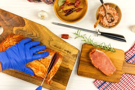 Butcher cutting pork meat on kitchen wooden cutting board. Kitchen utensils. Preparing meat for...