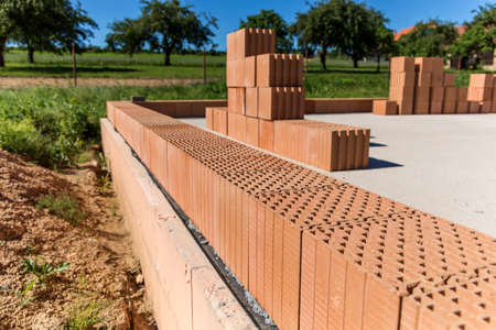 Construction site of a family house. Concrete base plate. Wall construction. Red bricks on a construction site. House construction.の写真素材
