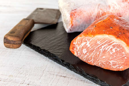 Frozen raw pork neck chops meat steak isolated on slate. Frozen uncooked slices of beef steaks,...