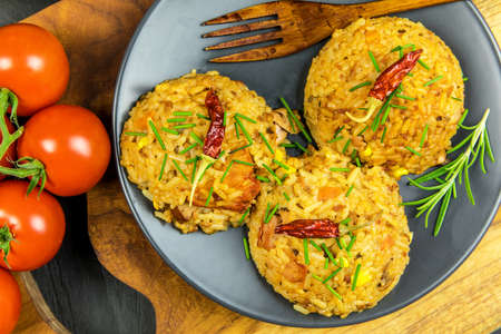 Red risotto with tomato and chili on black plate. Traditional meal. Home cooking. Spicy food. Chicken and pork in risotto.の写真素材