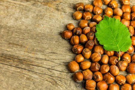 hazelnuts on wooden table, top view. Food background. Heap of many whole ripe brown hazel nuts....