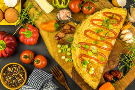 Egg omelette with bacon and sausage. Omelette with tomatoes, green onion on wooden plate. Frittata - Italian omelet. Top view. Flat lay.の写真素材