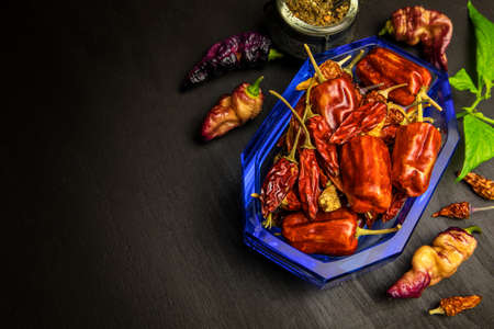 Different types of chili peppers on a black background. Vegetable background, copy space. Hot spices.の写真素材