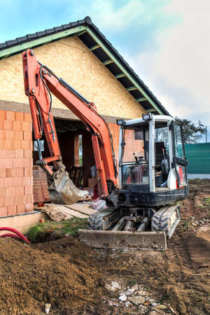 Mini excavator on construction site. Construction of a family house. Construction of a water supply...