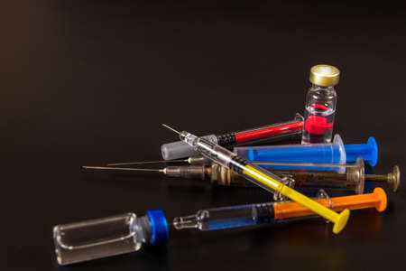 Vaccine and syringe injection on a black background. It use for prevention, immunization and treatment from corona virus infection. Influence prevention.の写真素材