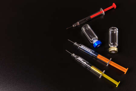 Vaccine and syringe injection on a black background. It use for prevention, immunization and treatment from corona virus infection. Influence prevention.の写真素材
