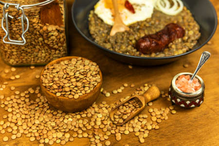 Lentils with sausage and chili. Grilled sausage and lentils with egg on a black plate. Legumes. Healthy food.の写真素材