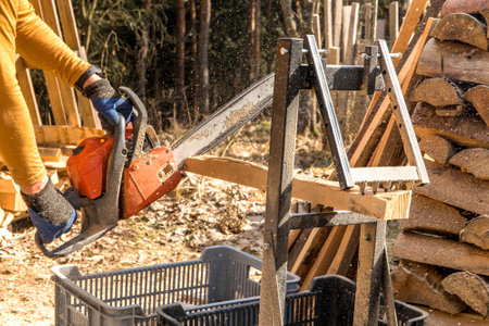 man cuts wood with a chainsaw. Preparing wood for winter. A lumberjack prepares wood for heating.の写真素材