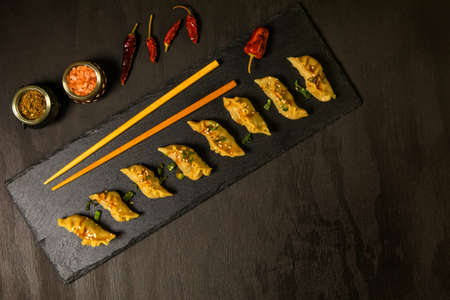 Fried dumplings gyoza with soy sauce, and chili. Chinese dumplings stuffed with meat. Homemade Meat Dumplings with soy sauce on black background.の写真素材