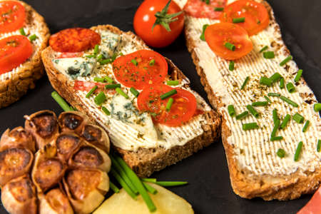 Healthy food rye bread with cream cheese and tomato. Sliced tomatoes with bread. Baked garlic with cheese and ham.の写真素材