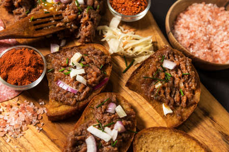 Traditional homemade French steak tartare of raw beef. Steak tartar with chopped onion and herbs on wooden board.の写真素材