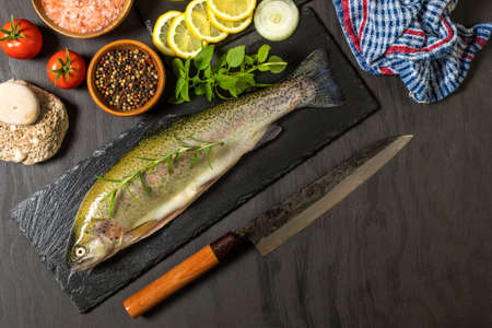 Raw trout on a black wooden table. Home preparation of trout.Healthy diet food. Fresh fish ready for grilling. Fishing industry.の写真素材