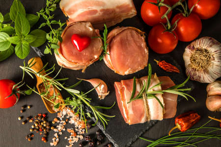 Fresh raw pork tenderloin with bacon on slate board. Meat ready for grilling. Diet food.の写真素材