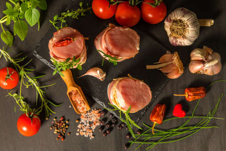 Fresh raw pork tenderloin with bacon on slate board. Meat ready for grilling. Diet food.の写真素材