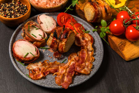 Grilled pork medallions with herbs and spices. Pork tenderloin with bacon. Grilled meat and tomatoes. Summer barbecue.の写真素材