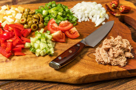 Tasty tuna salad with vegetables on wooden table. Vegetable salad with tuna. Preparing a healthy vegetable salad with fish. Diet food for athletes.の写真素材