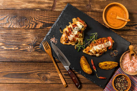 Baked roasted hasselback chicken stuffed with cheese and tomato. Portions of meat on the table. Keto diet. Baked chicken breast.の写真素材