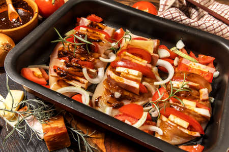 Raw chicken fillet on a cutting board with rosemary, spices, tomatoes and pepper. Portions of meat on the table. Keto diet.の写真素材