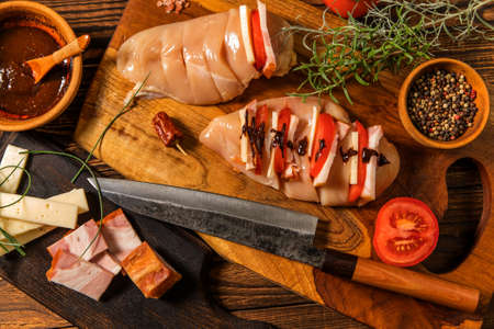 Raw chicken fillet on a cutting board with rosemary, spices, tomatoes and pepper. Portions of meat on the table. Keto diet.の写真素材