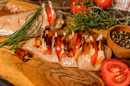 Raw chicken fillet on a cutting board with rosemary, spices, tomatoes and pepper. Portions of meat on the table. Keto diet.の写真素材