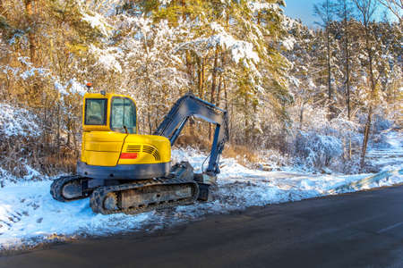 Excavator works in winter to repair the road. Excavator On Earthworks and Road Construction in the countryside in the Czech Republic. Road repair.の写真素材