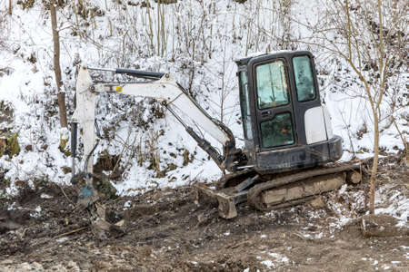 Excavator works in winter to repair the road. Excavator On Earthworks and Road Construction in the countryside in the Czech Republic. Road repair.の写真素材