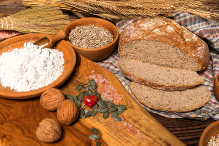 Homemade traditional wholemeal sourdough loaf of bread. Wholemeal sourdough bread on brown chopping board. Warm mood, concept of healthy homemade food.の写真素材