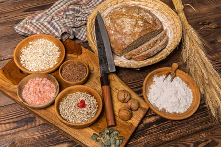 Homemade traditional wholemeal sourdough loaf of bread. Wholemeal sourdough bread on brown chopping board. Warm mood, concept of healthy homemade food.の写真素材