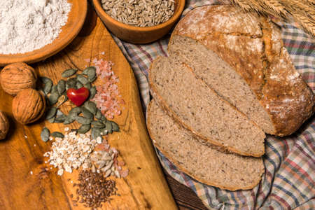 Homemade traditional wholemeal sourdough loaf of bread. Wholemeal sourdough bread on brown chopping board. Warm mood, concept of healthy homemade food.の写真素材