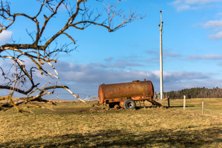 Water tank, drinker for cattle on pasture in Czech Republic. Empty pasture with rusty water tank. Cattle breeding on the farm.の写真素材