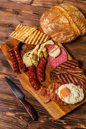 Different kinds of grilled sausages with egg. A selection of grilled gourmet meats on a rustic timber board. Grilled sausages with homemade bread.の写真素材