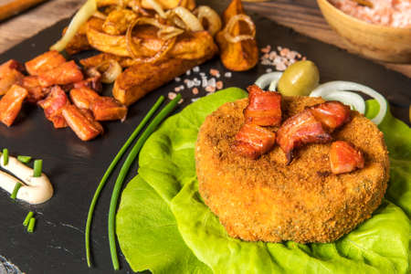 Baked camembert. Fried Camembert with chips and bacon. Fried cheese on green salad leaves.の写真素材