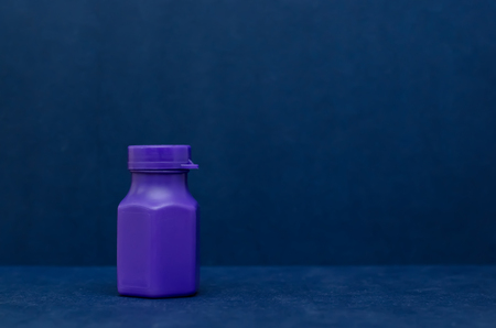 Little violet plastic bottle on the dark blue backgroundの写真素材